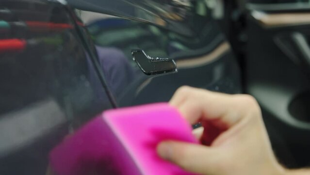 Close up shot. Process of applying a protective PPF film to a car. Hands of a professional applying a protective film of laminate. Close up shot