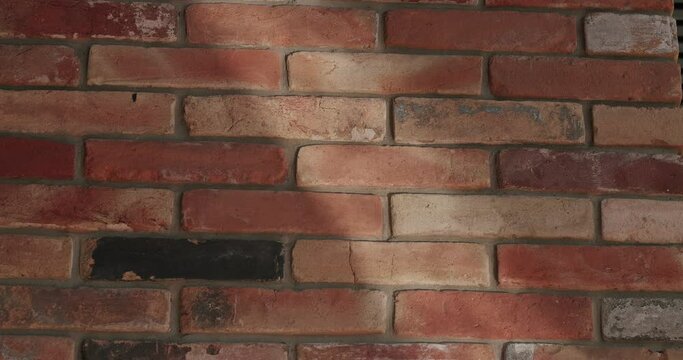 Textured red brick background with shadow. Closeup of water reflection and sun light on old house wall.