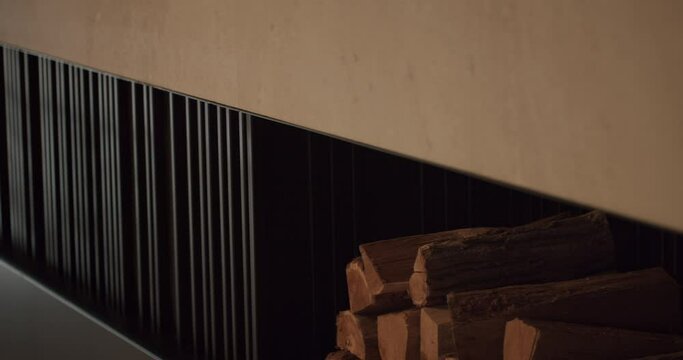 Closeup on stack of firewood at wall niche at modern apartment. Storage of woodpile for fireplace at cold season at home. Cozy decor element