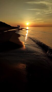 Zach&oacute;d słońca nad morzem.  Zachodzące słońce idealnie w linii brzegowej plaży, nad plażą. Zach&oacute;d słońca nad plażą. Kadr Pionowy