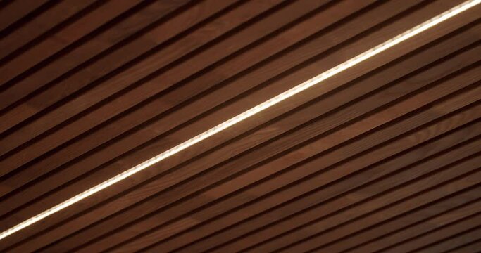 Ceiling with wooden planks and led light lamp at house. Decorative wood panels in interior of modern apartment