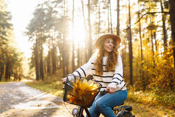 Happy young woman riding a bike, having fun in the autumn park. Concept of relaxation, nature....