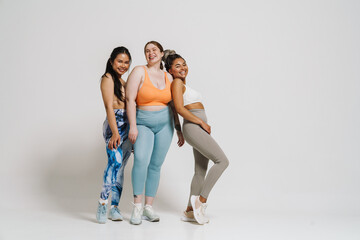 Three multinational women smiling and looking at camera while posing isolated over white wall - 649239951