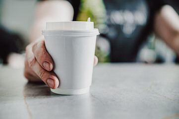 Barista hold a takeaway coffee in a paper cup