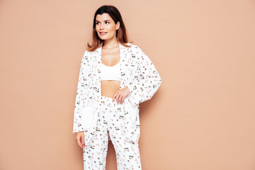 Obraz premium Young beautiful smiling female in trendy summer costume clothes. Carefree woman posing near beige wall in studio. Positive model having fun indoors. Cheerful and happy