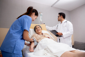 Fototapeta premium Doctor checkup and diagnostic while nurse measuring blood pressure with patient elderly at hospital ward, physician diagnosis disease of patient and care in clinic, medical and insurance concept.