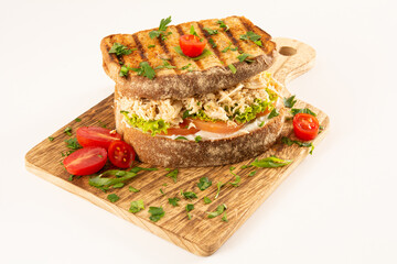 Chicken Breast Sandwich on Whole Grain Bread with Fresh Salad in a Wooden Table on a White Background in front view