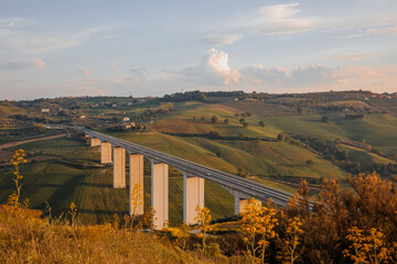 View of the E55 highway overpass. The overpass passes through the picturesque hills of the Abruzzo region in Italy. photo in yellow tones of sunset.