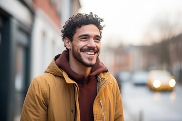 Obraz premium Portrait of a handsome young man with curly hair smiling outdoors.