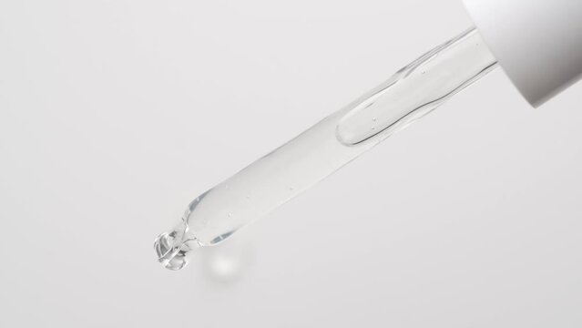 Macro shot of drop serum gel of is falling down from pipette on white background.
