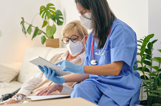 Crop Physician Interacting With Patient While Using Tablet At Ho