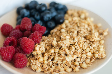 Muesli with blueberries and raspberries, close up. Granola with wild berries. Healthy eating. Bowl of oat flakes and blueberry and raspberry. Vitamin cereal breakfast. Homemade meal. Fitness food. 