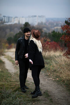 Full length image Happy couple walking in the park, girlfriend is pregnant, dressed in autumn clothes and hat, warm colors. Family concept.