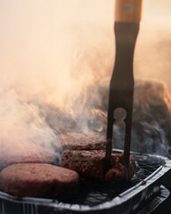 Burgers cooking on a bbq at sunset on the beach