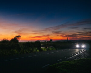 A car driving through the countryside at sunset