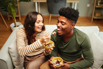 Young happy couple eating oatmeal on the sofa at home - 649266738