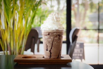 Mocha frappuccino in plastic cup with whipping cream on top. Coffee blended with chocolate. Closeup...