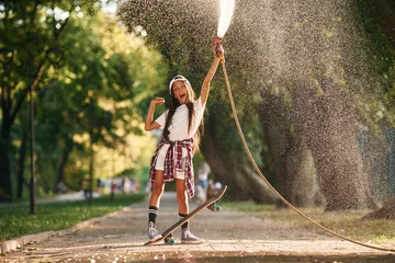 Foto op Canvas Cooling with the fresh water that goes from the pump. Happy little girl with skateboard outdoors © standret