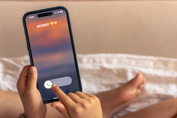 Smartphone in child hands with Incoming Mommy call on a screen.
