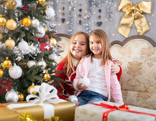 Fototapeta na wymiar Two girls hugging on sofa in Christmas interior