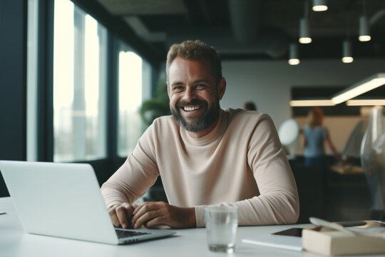 A Happy Businessman Looking At Camera While Working On His Computer 