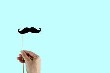 Hand holding Photo booth props, black mustache on color background