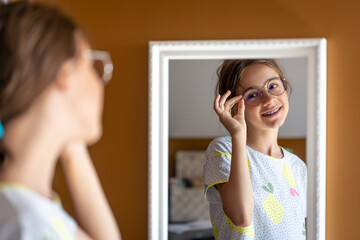 A teenage girl looks at herself in the mirror in the morning.