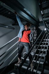 Fototapeta na wymiar Ethnic guy putting on jeans jacket on staircase