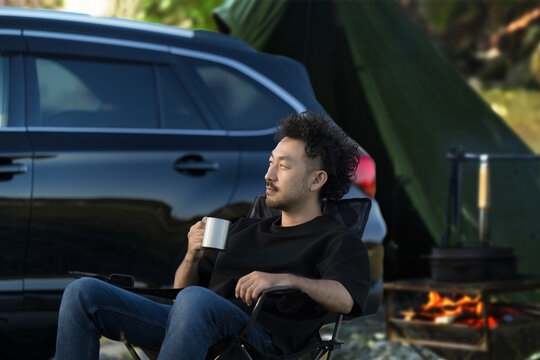 Asian (Japanese) man relaxing at campsite Image of auto-camping and solo camping