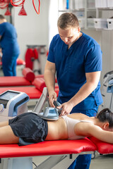 Electromagnetic therapy of the back, physiotherapist doctor uses medical equipment.
