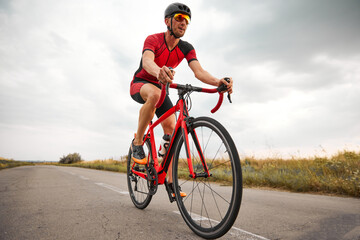 Competitive and motivated man, triathlete riding bicycle on road outdoors, training for marathon....