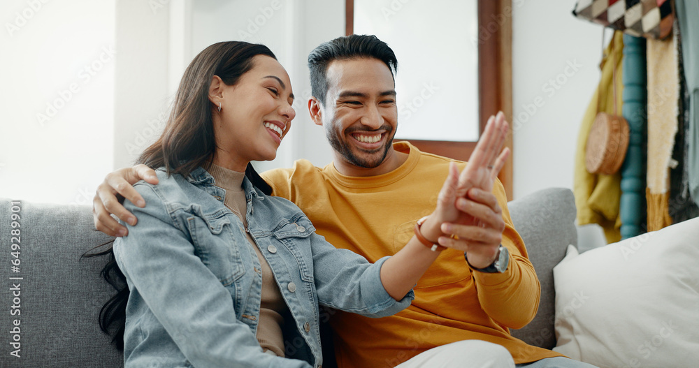 Poster Couple, engagement ring and relax on sofa, talk and happy in home living room, bonding or kiss cheek. Man, woman and smile with for planning, marriage and future together with care on couch in house