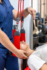 Female patient hanging on suspensions at rehabilitation center.
