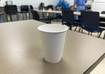 Recyclable paper cup, a symbol of eco-consciousness, sits on green grass amid littered plastic, highlighting environmental pollution. Conceptual image