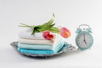 Light pastel blue towels, alarm clock, on a white background.