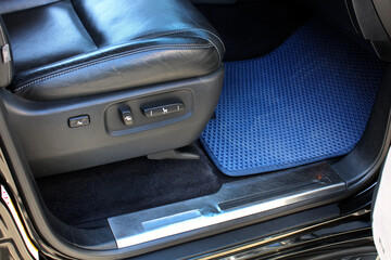 Сar carpet. SUV leather seat. Clean car floor mats of blue carpet under front passenger seat in the workshop for the detailing vehicle before dry cleaning. Auto service industry. Interior of lux SUV.