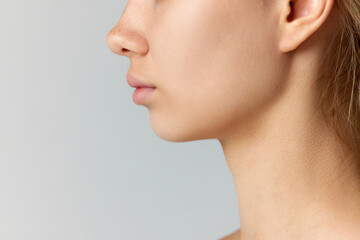 Cropped side view image of female face isolated over grey studio background. Reduction of double...