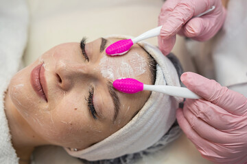 beautician doing beauty treatment her woman client by facial care at spa salon