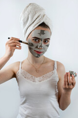 caucasian woman applying clay mask with brush on her face, skin care