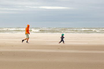 Kleinkind und Papa spielen im Sturm am Strand