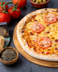 Napolitan style pizza over stone background with tomatoes, olives and oregano