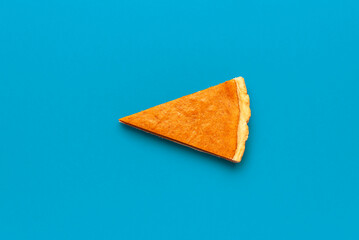 Pumpkin pie slice isolated on a blue background