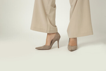 Female model wearing beige smart casual high rise wide leg trousers with high heels. Studio shot.	