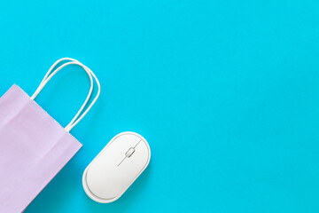 Computer mouse and paper bag on a blue background, top view.