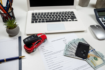 toy car with key, dollar and laptop, document for buy or rent auto at office desk - obrazy, fototapety, plakaty