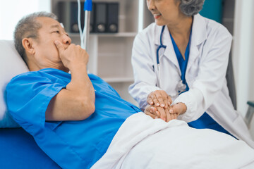 Senior elderly male patient and asian people mature woman doctor, showcasing importance of healthcare expertise and patient support. caring senior doctor assisting elderly patient in hospital bed