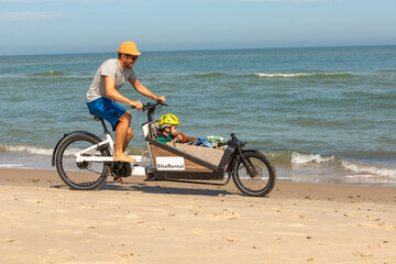 Fototapeta na wymiar Papa und Kind haben Spaß mit dem Lastenrad am Strand,Skagen,Dänemark