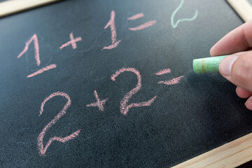 close up hand write primary simple mathematical equation. Math chalkboard