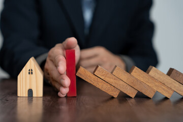 insurance with hands protect domino. Businessman hands stop dominoes falling in house crisis....