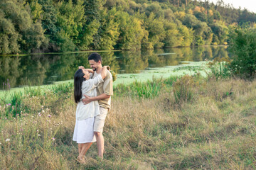 Happy man and woman in nature by the river enjoying each other.